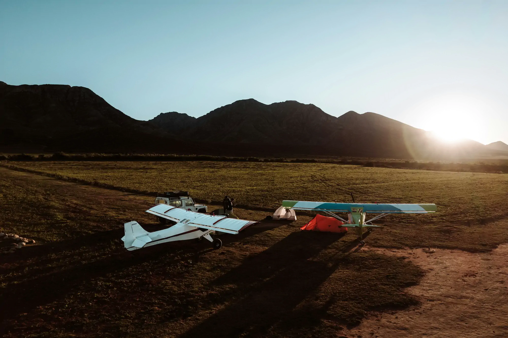 Two taildraggers plane camping in a field